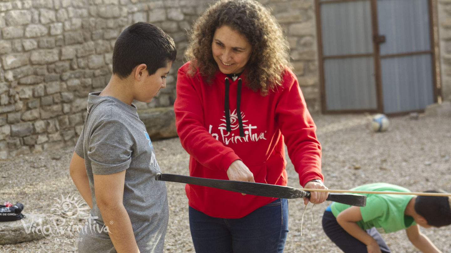 Eva enseñando a un niño a tirar con arco